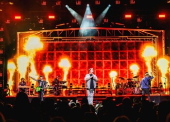 A live concert with bright flames and intense stage lighting.